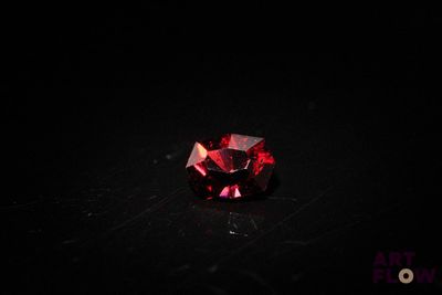 a close up of a red diamond on a black surface