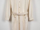 une photo d'un trench-coat blanc suspendu à un cintre