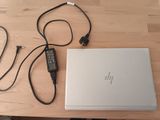 un ordinateur portable et un chargeur posés sur une table en bois