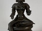 statue of a woman sitting on a rock with a snake in her hand