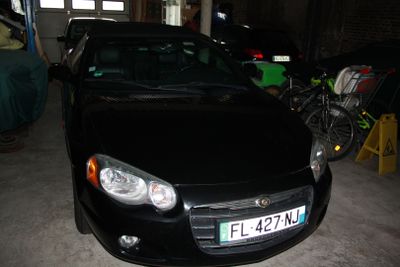une voiture noire garée dans un garage à côté d'un vélo