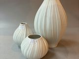 three white vases sitting on a table next to each other