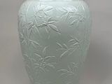 a large green vase with bamboo leaves on it