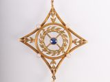 a close up of a gold pendant with a blue stone in the center