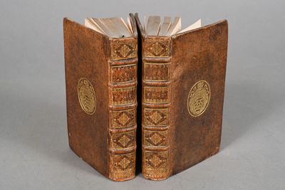 two old books sitting on top of each other on a table