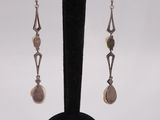 a close up of a pair of earrings on a black stand