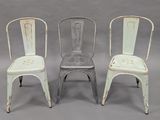 three metal chairs sitting next to each other on a gray surface