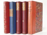several old books are lined up in a row on a white surface