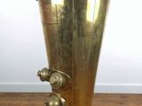 an antique brass water dispenser on a wooden floor