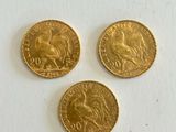 three gold coins are sitting on a white surface