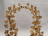 une image représentant une couronne dorée ornée de feuilles et de fleurs, posée sur un socle rouge