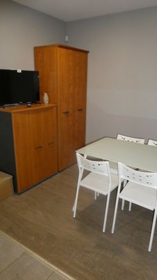 une table et des chaises blanches dans une pièce équipée d'une télévision