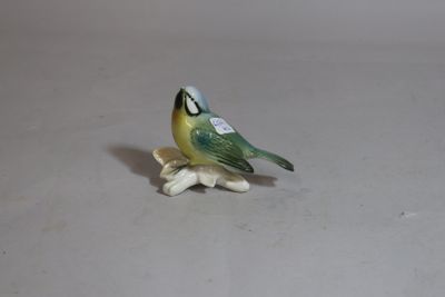 a small figurine of a bird sitting on a flower