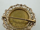 an image of a gold broochle with a coin in it