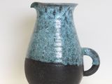 a blue and black vase sitting on a white surface