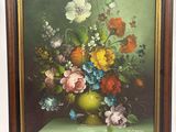 un tableau représentant des fleurs dans un vase vert posé sur un chevalet