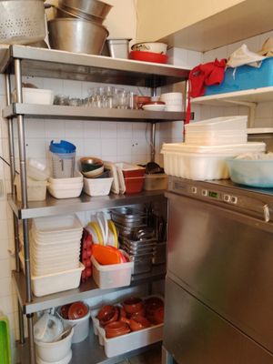 une étagère en acier inoxydable dans une cuisine, avec de la vaisselle et des casseroles
