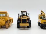 three toy construction vehicles that are on a white surface