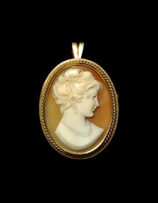 un gros plan du visage d'une femme sur un pendentif plaqué or