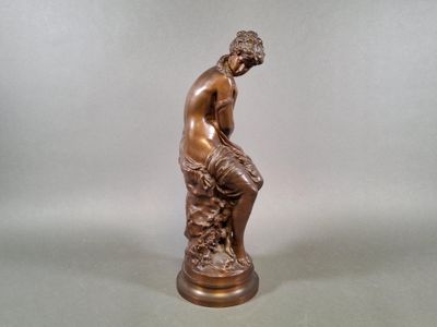 bronze statue of a man sitting on a rock with his hands on his knees