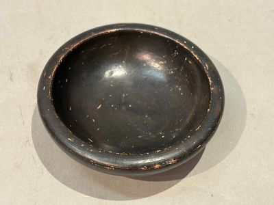 a black bowl sitting on a table with a white table cloth
