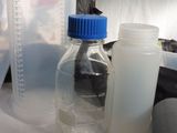 a bottle of liquid next to a bottle of water on a table