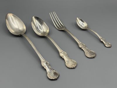 six cuillères et une fourchette en argent sur une surface grise