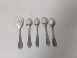 four spoons and a fork are lined up on a table