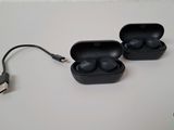 two black ear buds sitting on a table with a charger
