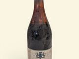 an old bottle of wine sitting on top of a white surface