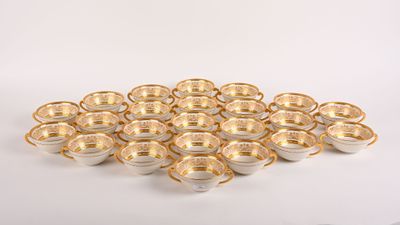 une pile de tasses et de soucoupes dorées et blanches posées sur une surface blanche