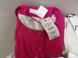 a pink jacket and a white shirt sitting on a bed