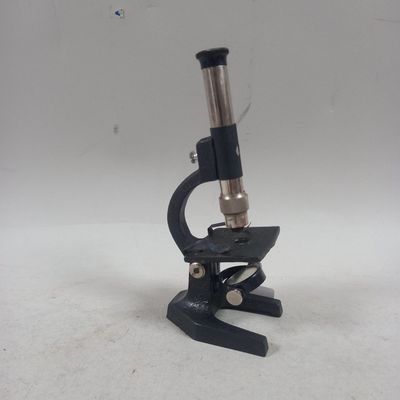 Gros plan sur un microscope posé sur une table, sur fond blanc
