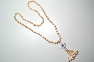 un long collier de perles auquel est suspendu un pompon