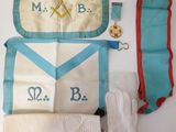 three masonic aprons and a pair of gloves are laid out on a table