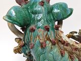 a green and brown statue of a ram on a table