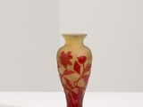 un vase rouge posé sur une surface blanche, avec un fond blanc