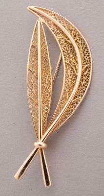 a close up of a gold brooch with a leaf on it