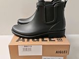 des bottes en caoutchouc noires posées sur une boîte, sur une surface blanche