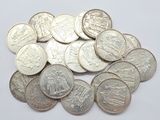 a close up of a pile of silver coins on a white surface