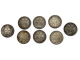 a group of five silver coins sitting on top of a white surface