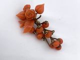 a close up of an orange flower broochle on a white surface