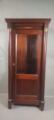 une armoire en bois avec une porte vitrée, placée dans un coin