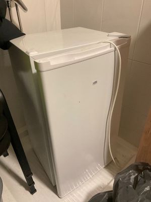 un petit réfrigérateur blanc dans le coin d'une pièce