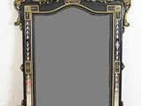 un miroir au cadre noir et or ouvragé accroché à un mur blanc
