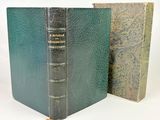 un vieux livre posé à côté d'un livre fermé sur une surface blanche