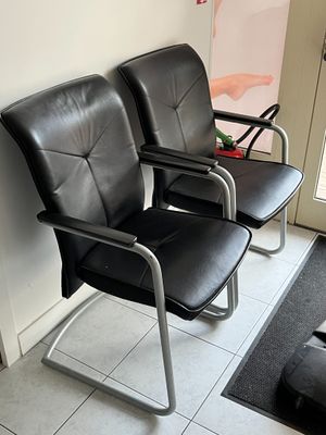 deux fauteuils en cuir noir placés l'un à côté de l'autre dans une salle d'attente