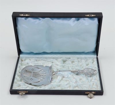 an antique silver spoon and spoon rest in a black case