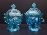 une paire de bonbonnières en verre bleu avec couvercles, posées sur un support noir