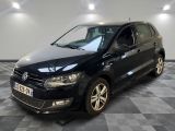La Volkswagen Polo noire est garée dans une pièce au sol carrelé en damier.